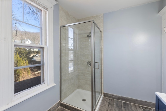 full bath featuring a shower stall, baseboards, and wood finished floors