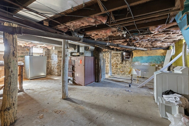 unfinished below grade area featuring washer / dryer and freestanding refrigerator