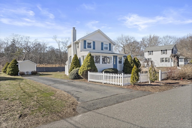 view of front of property with a fenced front yard, driveway, and a chimney