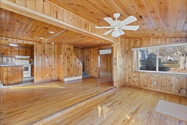 unfurnished living room with wooden walls, a ceiling fan, light wood-style flooring, and wooden ceiling