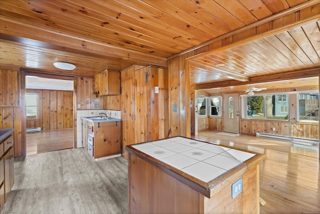kitchen with a sink, tile countertops, light wood-style floors, wooden ceiling, and baseboard heating