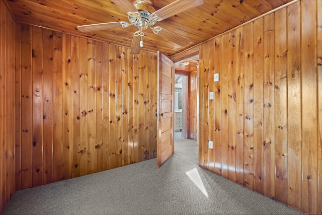 carpeted empty room with wood walls, wooden ceiling, and a ceiling fan