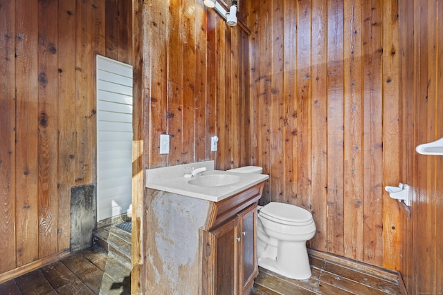 bathroom featuring wooden walls, toilet, vanity, and hardwood / wood-style floors