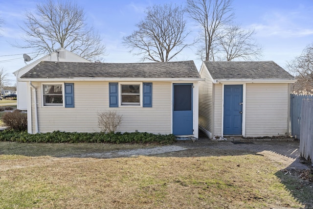 exterior space with a shingled roof, a front lawn, and fence