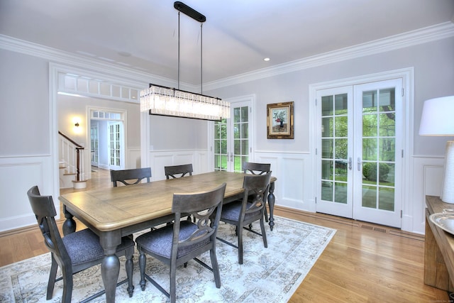 dining space featuring french doors, a decorative wall, ornamental molding, stairway, and healthy amount of natural light