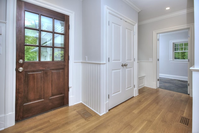 entrance foyer featuring light wood-style floors, crown molding, wainscoting, a decorative wall, and recessed lighting