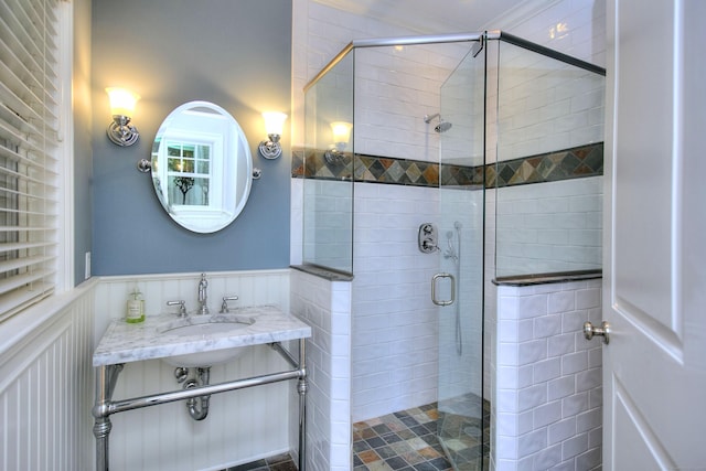 full bathroom featuring a sink, a stall shower, and wainscoting