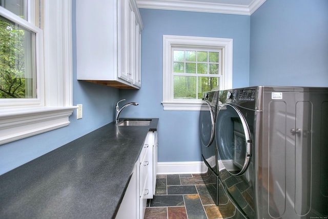 washroom featuring cabinet space, washer and clothes dryer, baseboards, ornamental molding, and dark stone finish floors