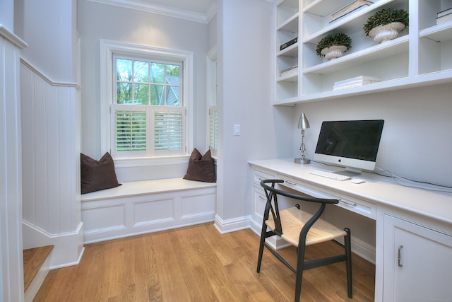 office area with built in study area, light wood-style floors, and ornamental molding