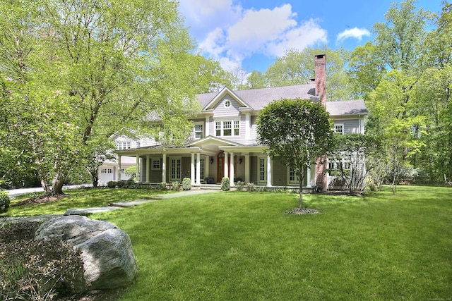 back of house featuring a porch, a yard, and a chimney