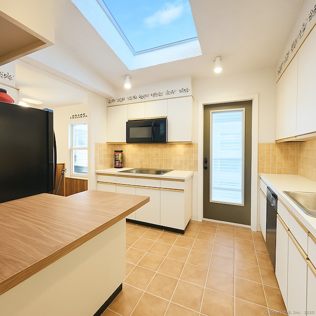 kitchen featuring black appliances, white cabinetry, backsplash, light countertops, and a skylight