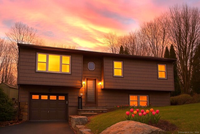 bi-level home with a lawn, driveway, and a garage