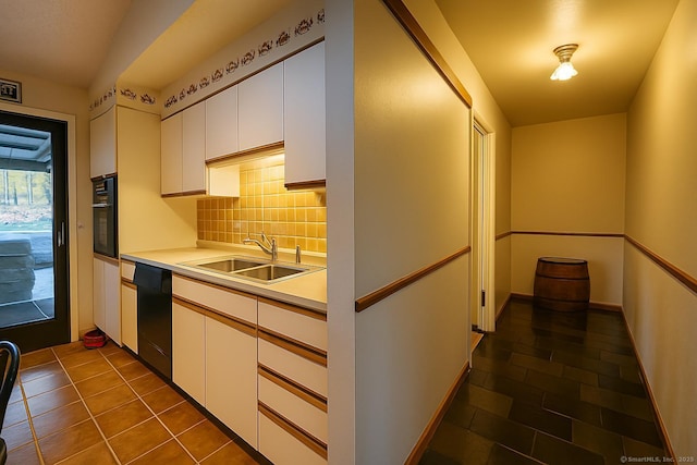 kitchen featuring tasteful backsplash, white cabinets, a sink, light countertops, and black appliances