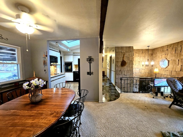 dining area featuring lofted ceiling with skylight, ceiling fan, and light carpet