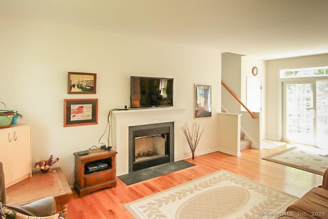 living room with stairway, a fireplace with flush hearth, and wood finished floors