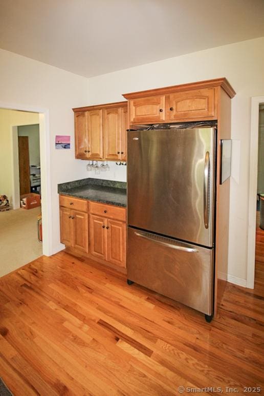 kitchen featuring dark countertops, light wood-style floors, brown cabinets, and freestanding refrigerator
