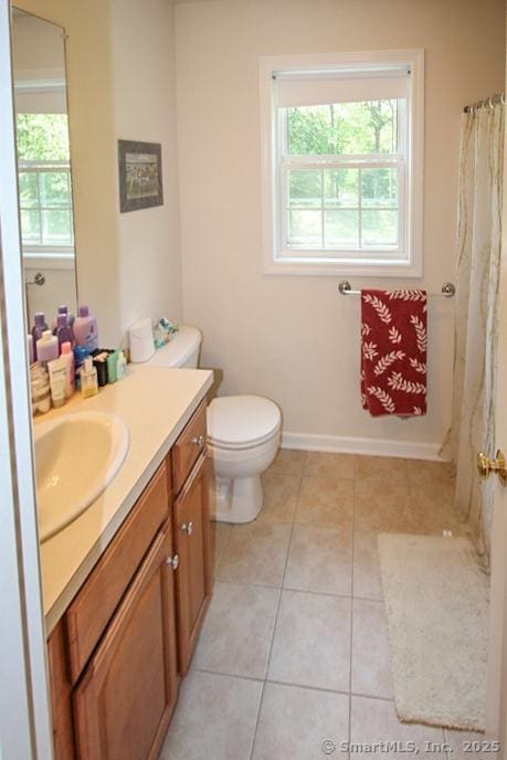 bathroom with tile patterned flooring, vanity, toilet, and a healthy amount of sunlight