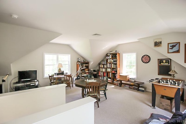office space featuring vaulted ceiling, a healthy amount of sunlight, visible vents, and light carpet