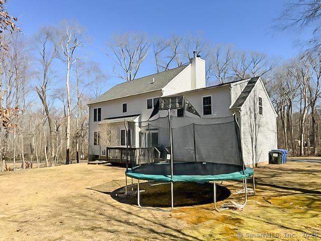 rear view of house with a deck, a chimney, and a trampoline