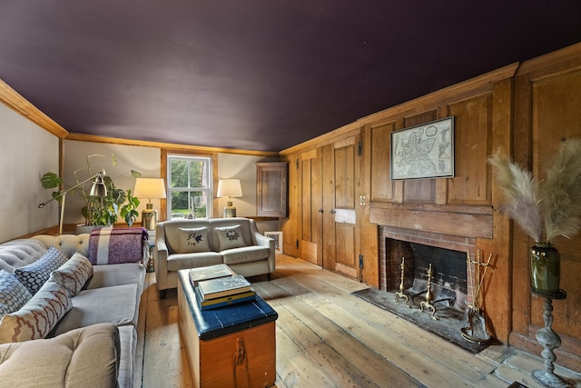58 Middle Haddam Rd, East Hampton, CT 06456 - living area with a fireplace with raised hearth, ornamental molding, light wood-style floors, and wooden walls