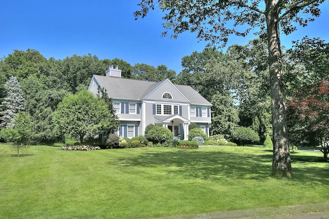 view of front of house featuring a chimney and a front lawn