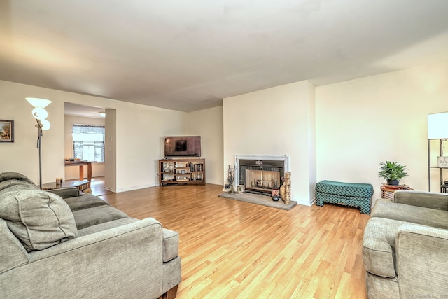living room featuring a fireplace with raised hearth and wood finished floors
