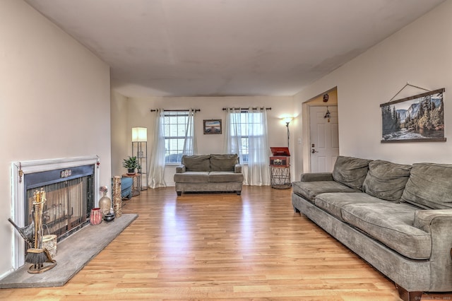 living room featuring light wood-style flooring and a fireplace with raised hearth