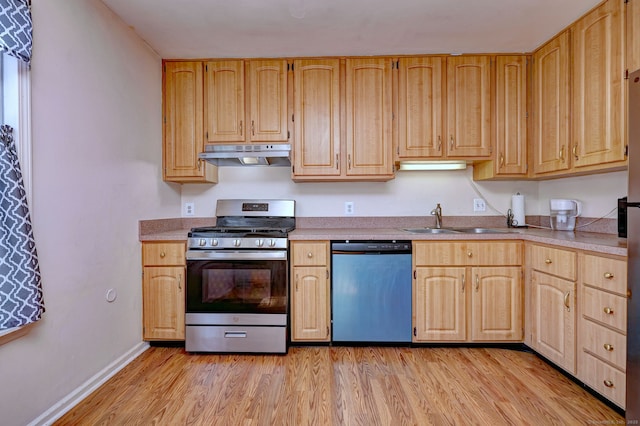 kitchen with light wood finished floors, dishwasher, under cabinet range hood, stainless steel gas range oven, and a sink
