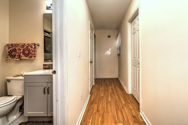 hall with light wood-style flooring and baseboards