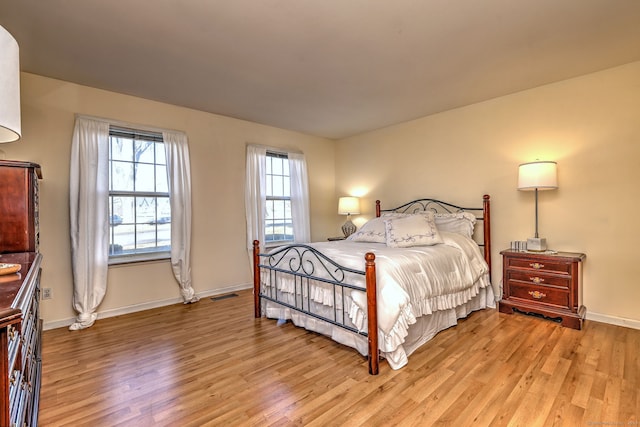 bedroom featuring baseboards, visible vents, and light wood-style flooring