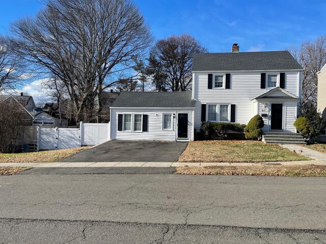 view of front of home with a gate, fence, driveway, a shingled roof, and a chimney
