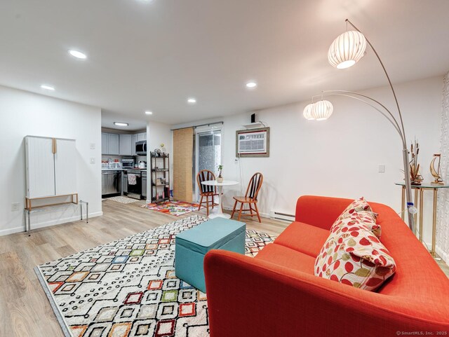 living area with baseboards, a wall mounted AC, light wood-style flooring, recessed lighting, and baseboard heating
