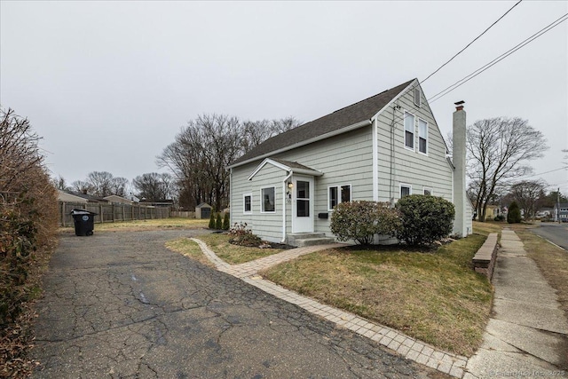 view of side of property featuring a chimney, driveway, and fence