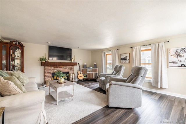 living room with dark wood finished floors, a brick fireplace, and baseboards