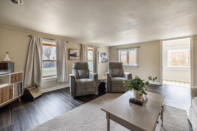 living area with dark wood-style floors, a textured ceiling, and baseboards