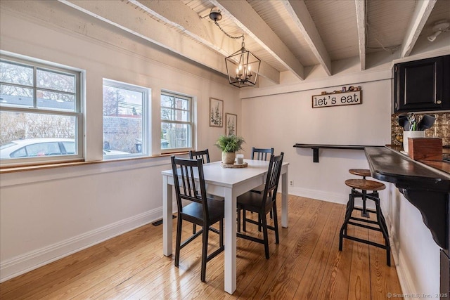 dining room with light wood-style flooring, baseboards, beamed ceiling, and a chandelier