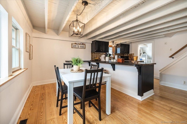 dining space with visible vents, beamed ceiling, light wood-style flooring, baseboards, and a chandelier