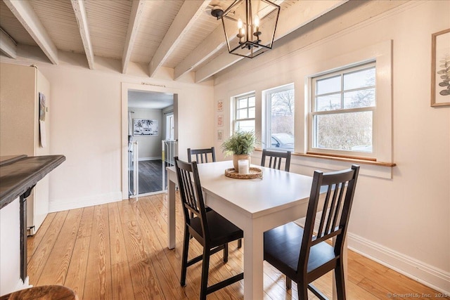 dining area featuring beam ceiling, light wood-style flooring, baseboards, and a chandelier