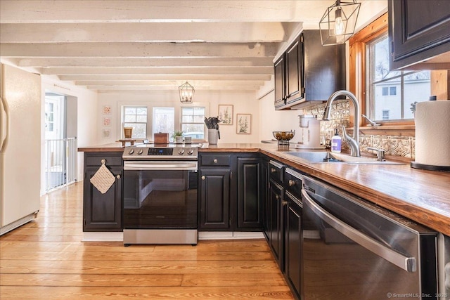 kitchen with light wood-style flooring, appliances with stainless steel finishes, a peninsula, and a sink