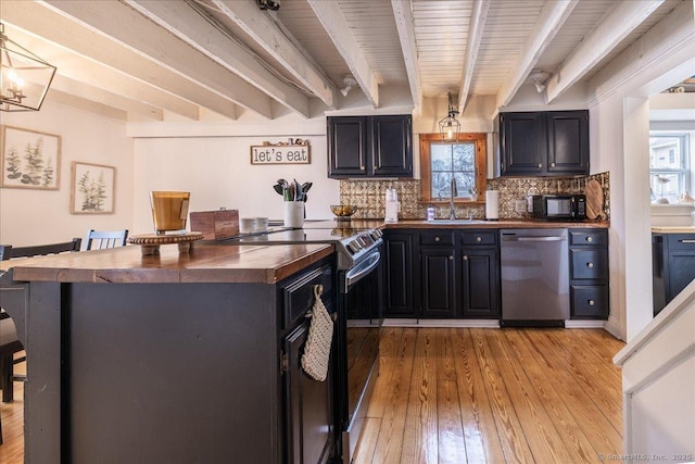 kitchen featuring beam ceiling, a breakfast bar, a sink, stainless steel appliances, and decorative backsplash