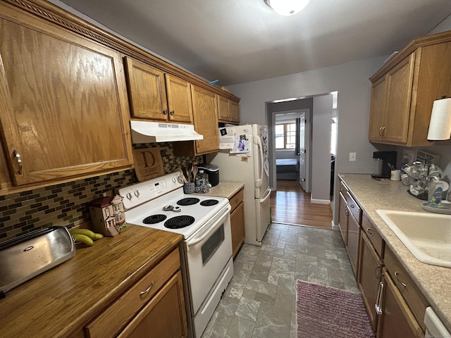 173 Russo Ave Unit 610, East Haven, CT 06513 - kitchen with white appliances, under cabinet range hood, decorative backsplash, stone finish floors, and brown cabinetry