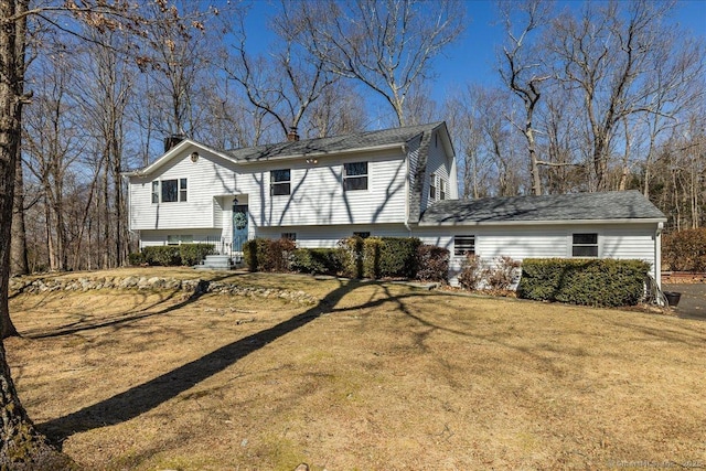 bi-level home with a front yard, entry steps, and a chimney