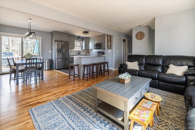 living area with baseboards, visible vents, and light wood-style flooring