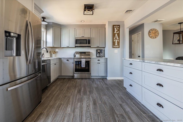 kitchen featuring dark wood-style flooring, gray cabinetry, backsplash, visible vents, and appliances with stainless steel finishes