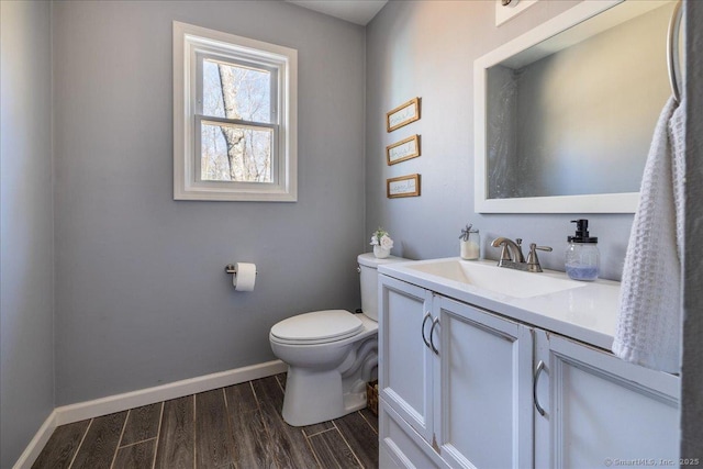 half bath featuring baseboards, wood finished floors, toilet, and vanity