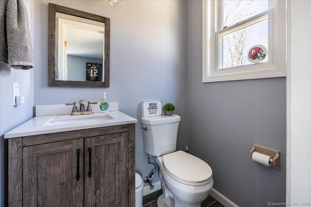 half bath featuring toilet, vanity, and baseboards
