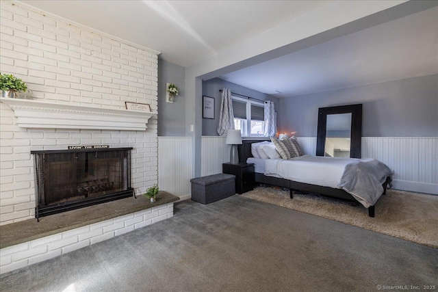 carpeted bedroom featuring wainscoting and a fireplace