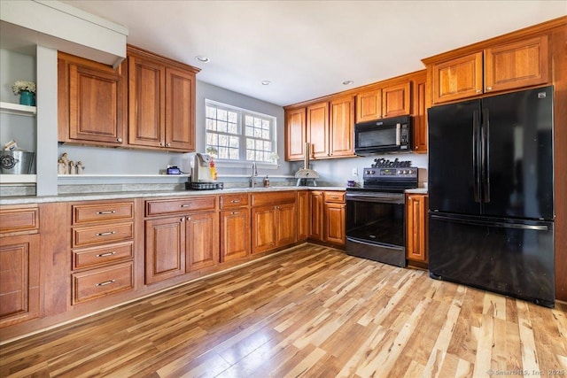 kitchen featuring a sink, light wood-style floors, black appliances, and brown cabinets