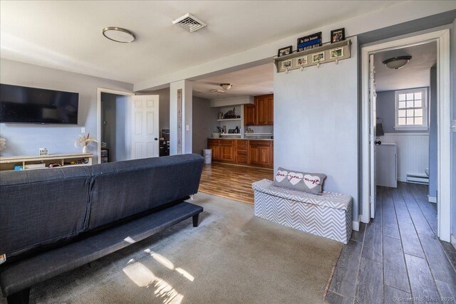 living area featuring visible vents, baseboard heating, and wood finished floors