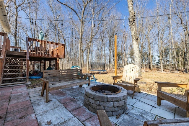 view of patio with stairs, a fire pit, a trampoline, and a deck